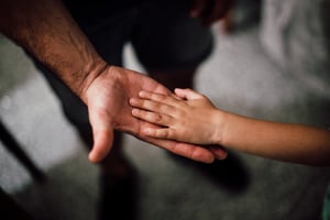 Adult hand holding a child's hand